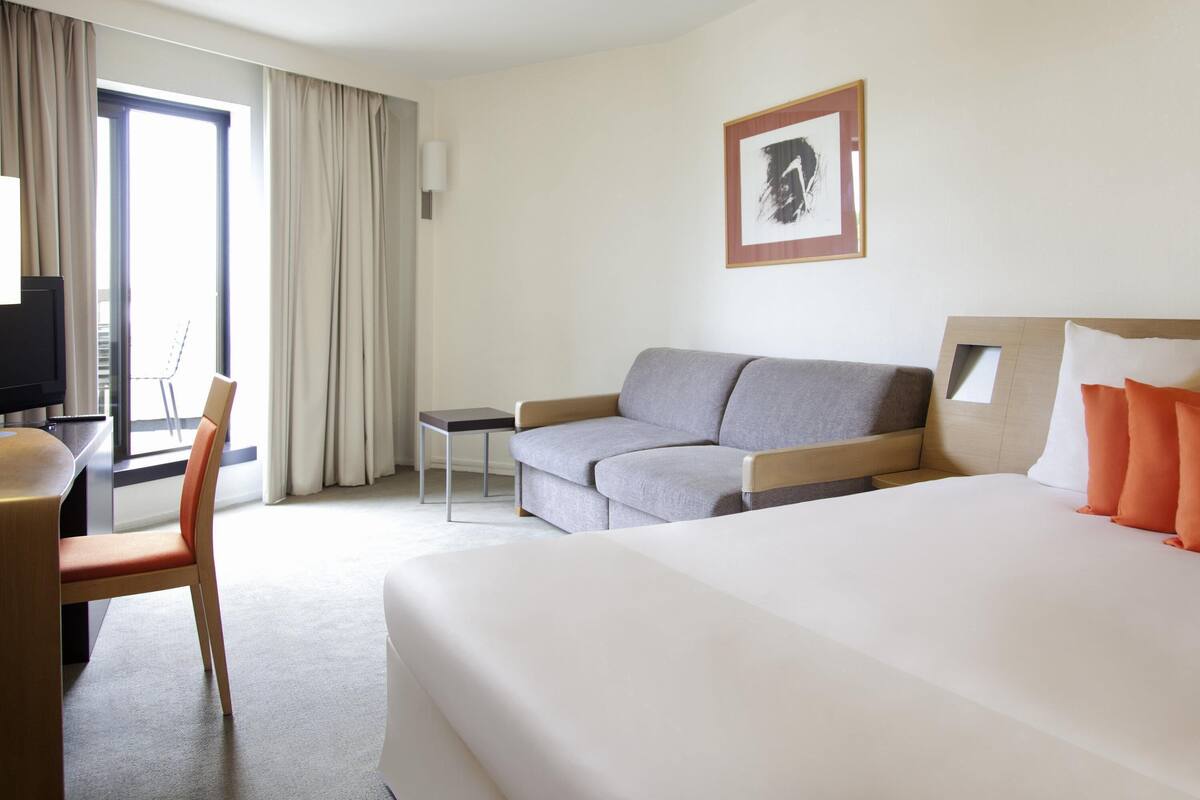 Ein Hotelzimmer mit einem Bett, einer Couch, einem Schreibtisch, einem Stuhl und einem Fernseher.