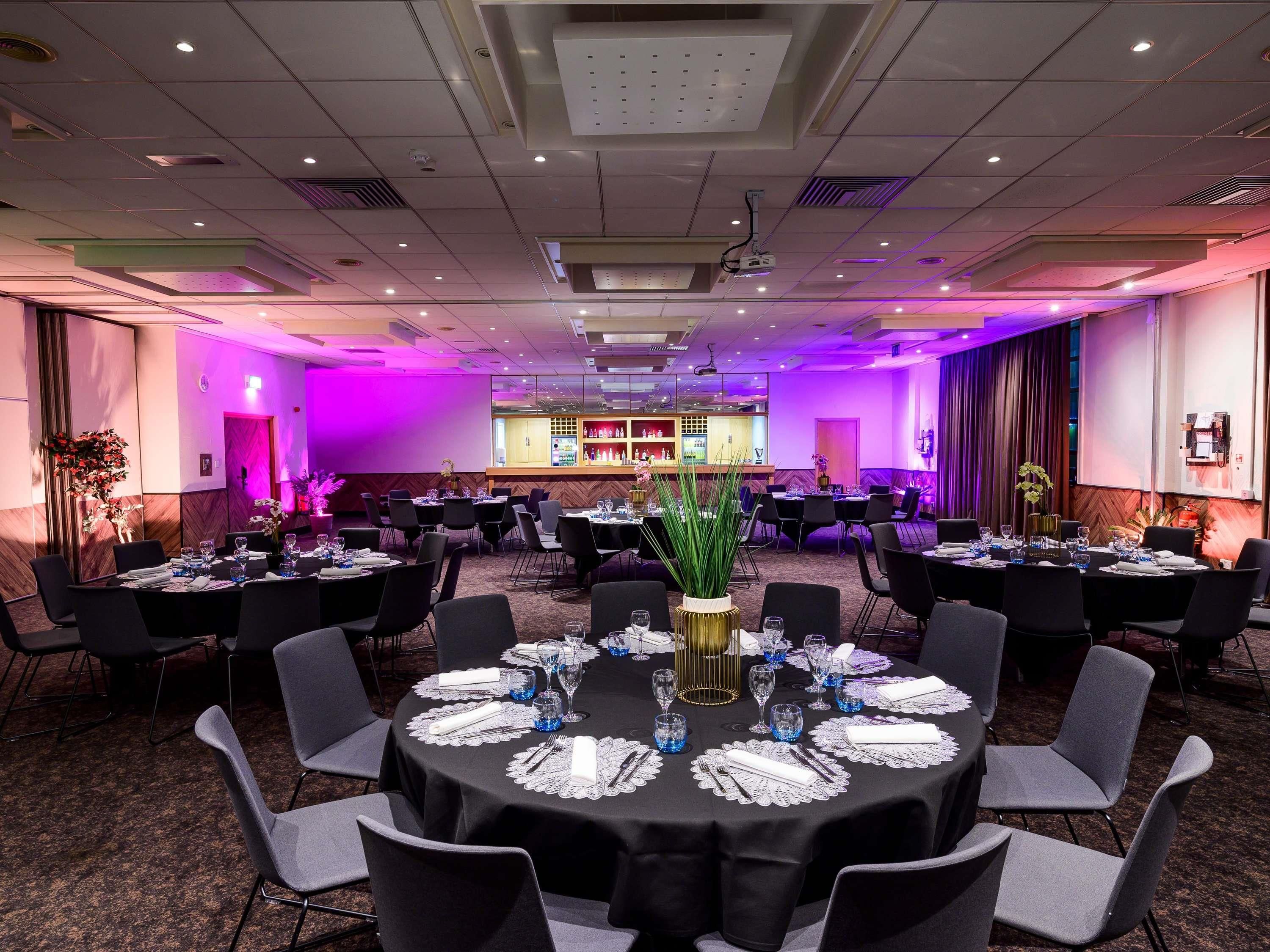 A conference room with round tables, chairs, and a bar area.