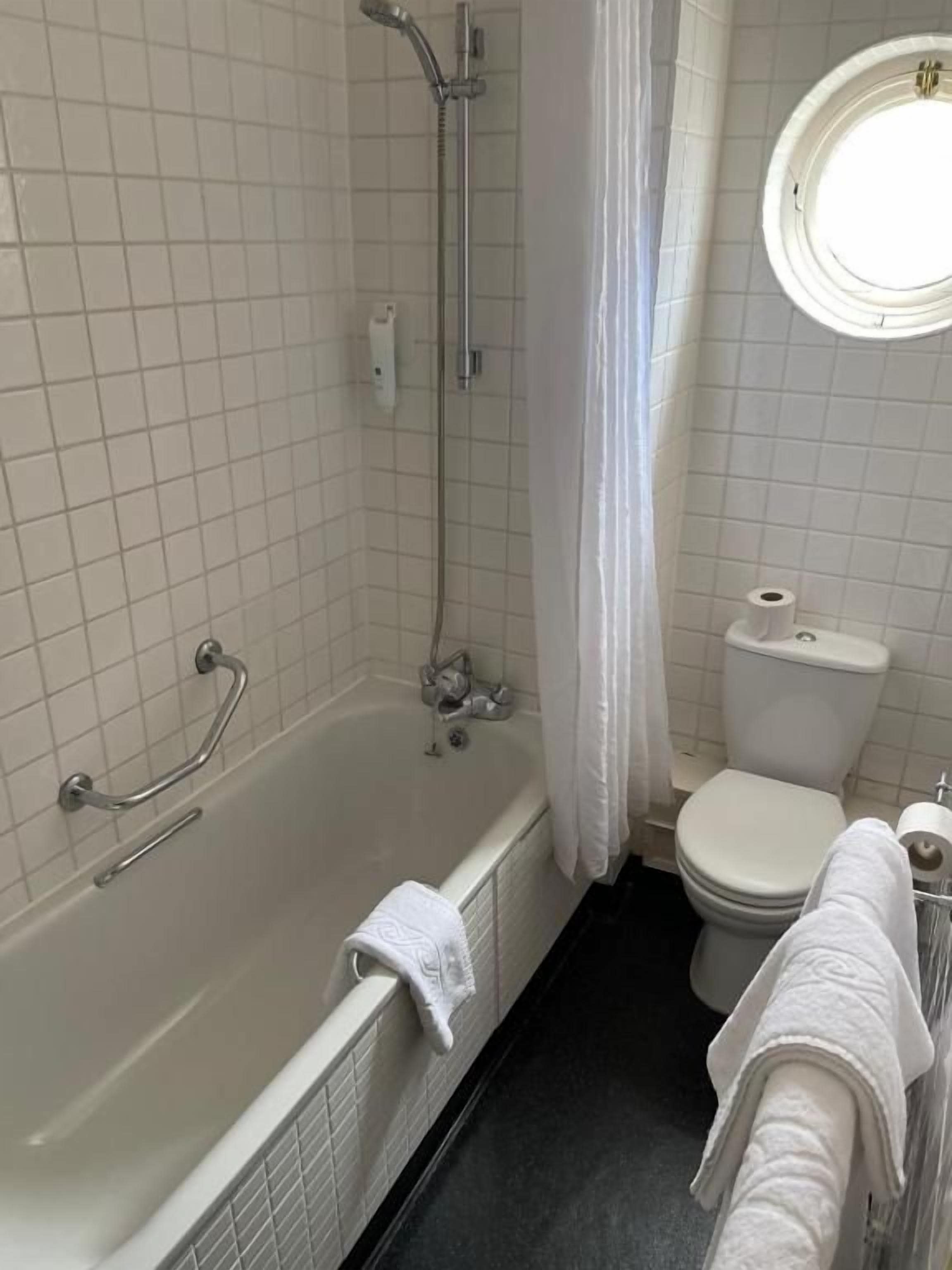 Een badkamer met een bad, toilet en douche.