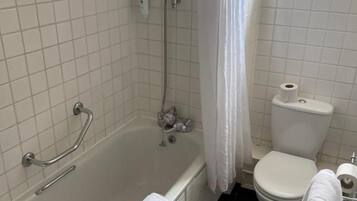 Een badkamer met een bad, toilet en douche.