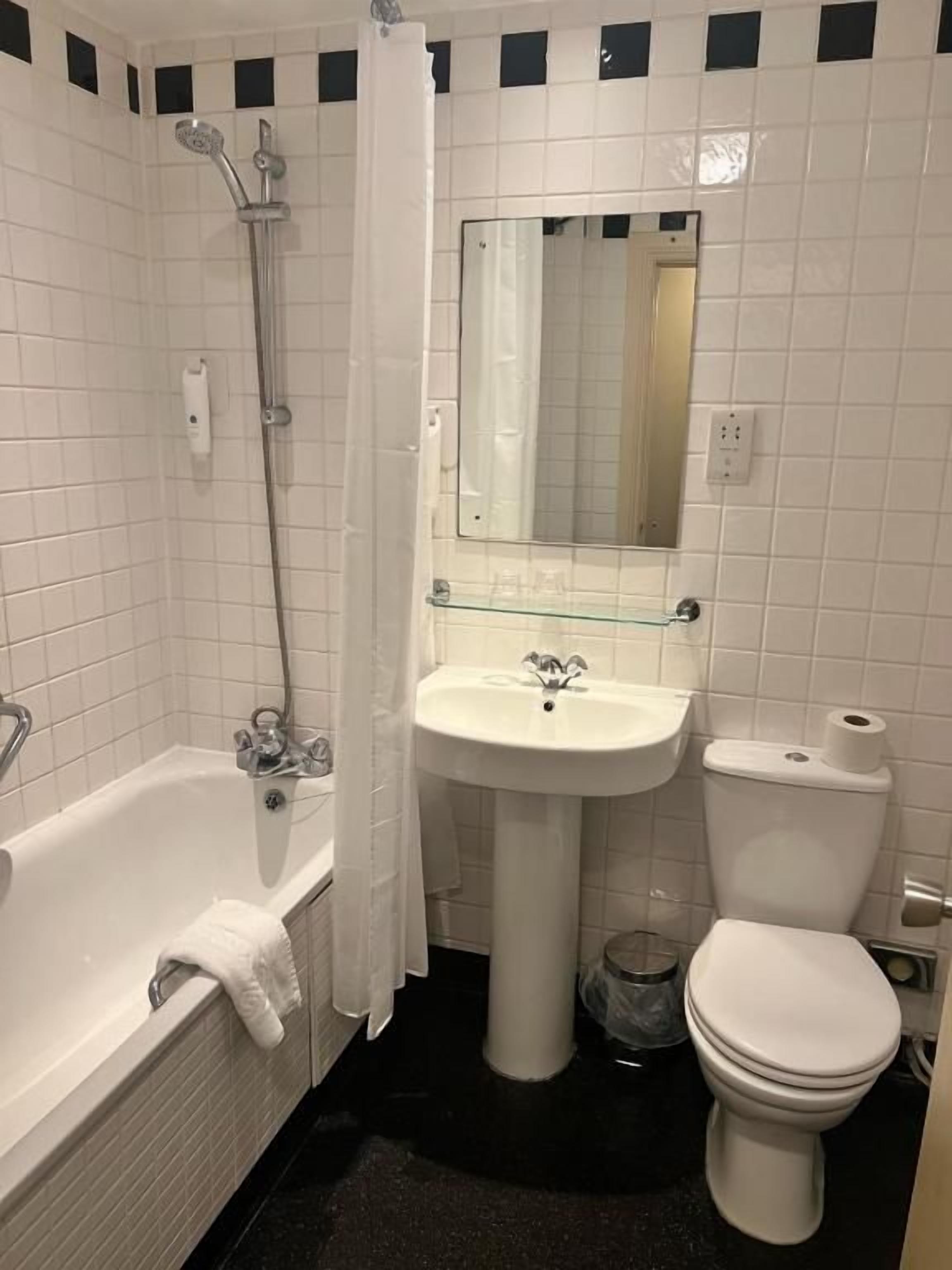 A bathroom with a bathtub, a sink, a toilet, and a mirror.