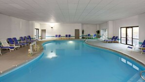 An indoor swimming pool with blue water, surrounded by blue and white lounge chairs. - Days Inn & Suites by Wyndham Northwest Indianapolis (Indianapolis)