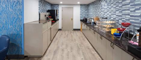 Une cuisine moderne avec un plancher en bois, des meubles de couleur claire et un mur orné d’un motif bleu.