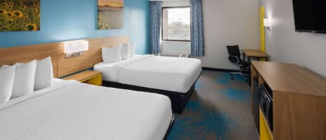 Habitación de hotel con dos camas, un escritorio, una silla, un televisor y una ventana con cortinas.