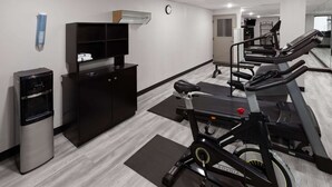 A gym with exercise equipment, a water dispenser, and a TV on a cabinet. - Days Inn & Suites by Wyndham Northwest Indianapolis (Indianapolis)
