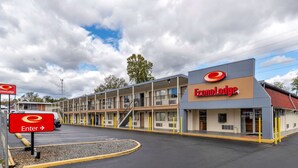 Ein Motel mit einem zentralen Eingang, mehreren Etagen und einem Parkplatz.
