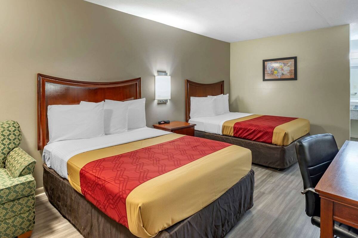 Une chambre d’hôtel avec deux lits, un bureau, une chaise et un petit canapé.