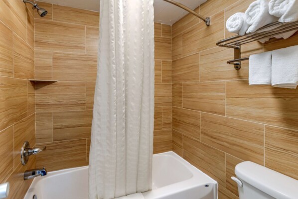 Uma casa de banho moderna com banheira, chuveiro e sanita.