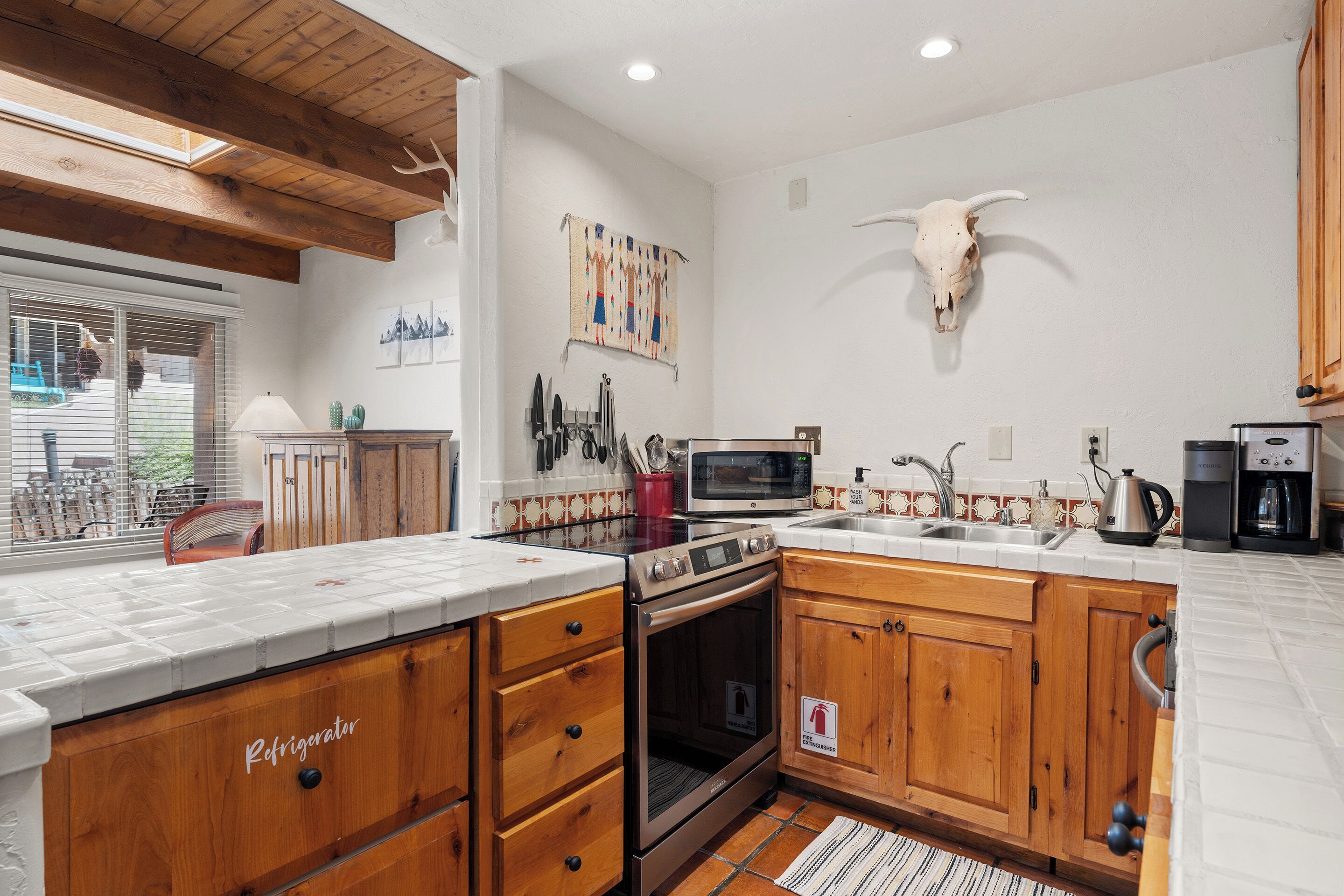 A kitchen with wooden cabinets, a stainless steel refrigerator, a microwave, and a stove.