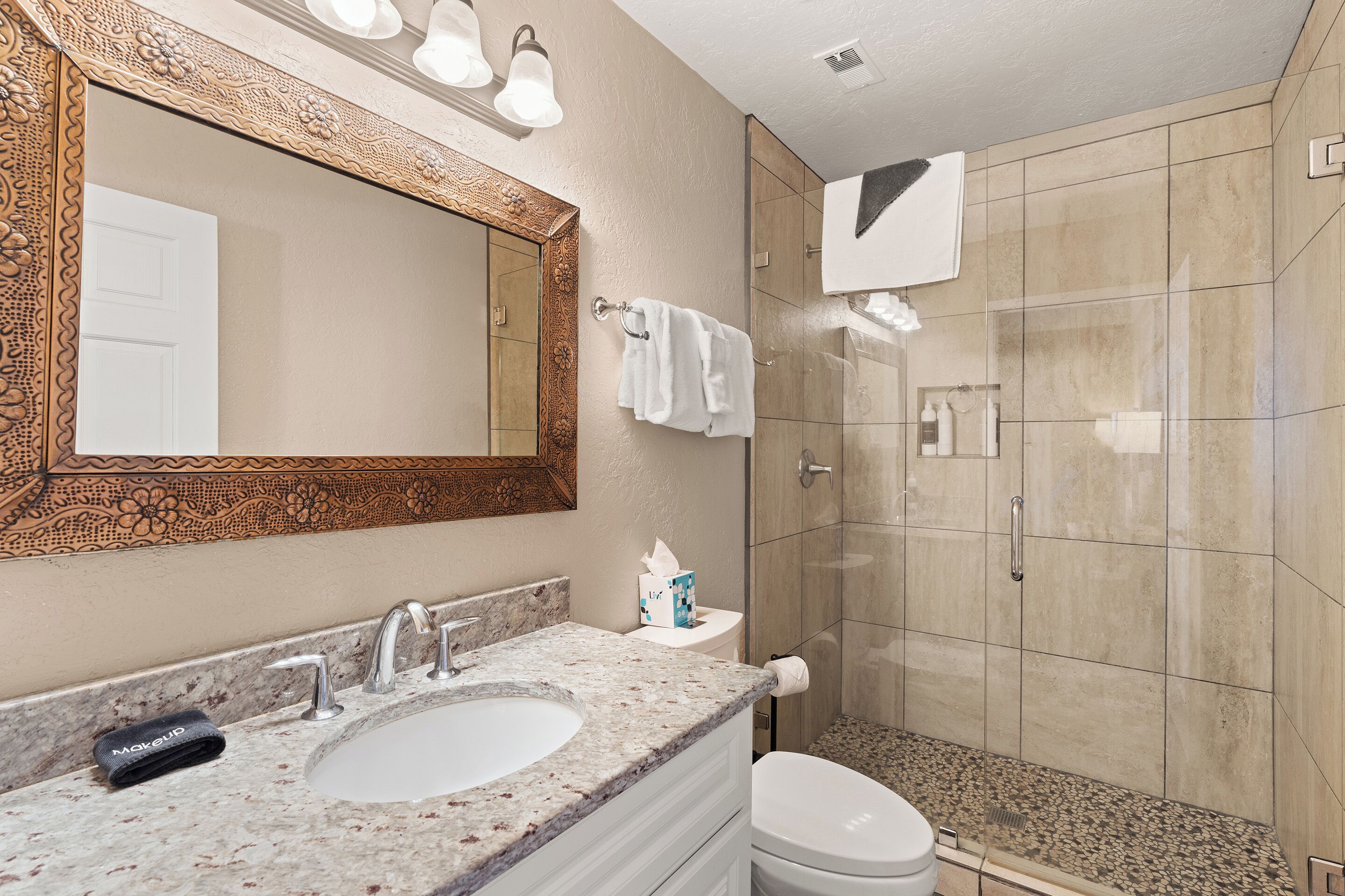 A bathroom with a large mirror, two sinks, a toilet, and a shower area.