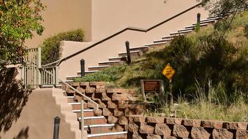 A staircase with stone railings and a caution sign for uneven sidewalks.