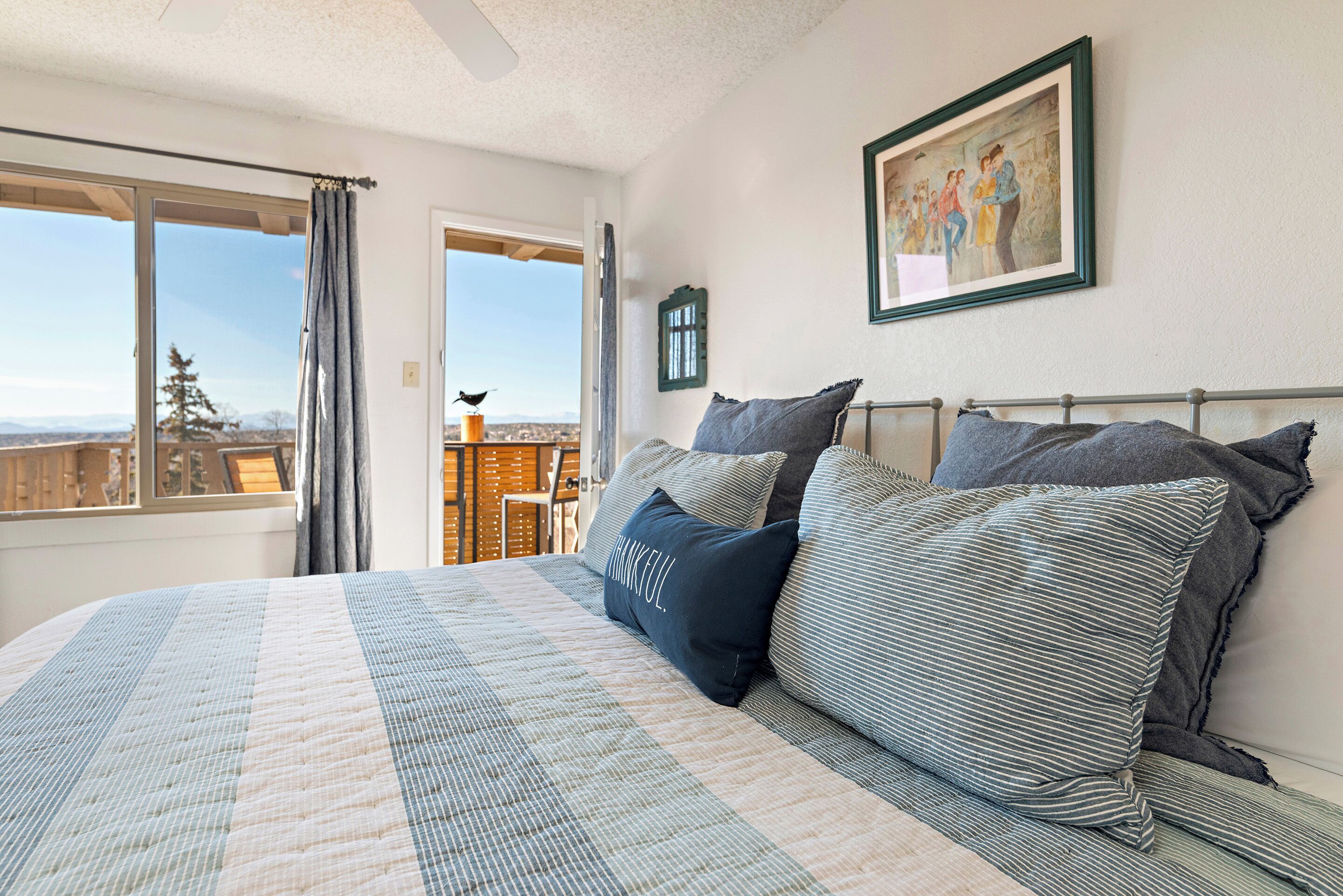 Un dormitorio con una cama grande, vistas por una ventana y un cuadro en la pared.