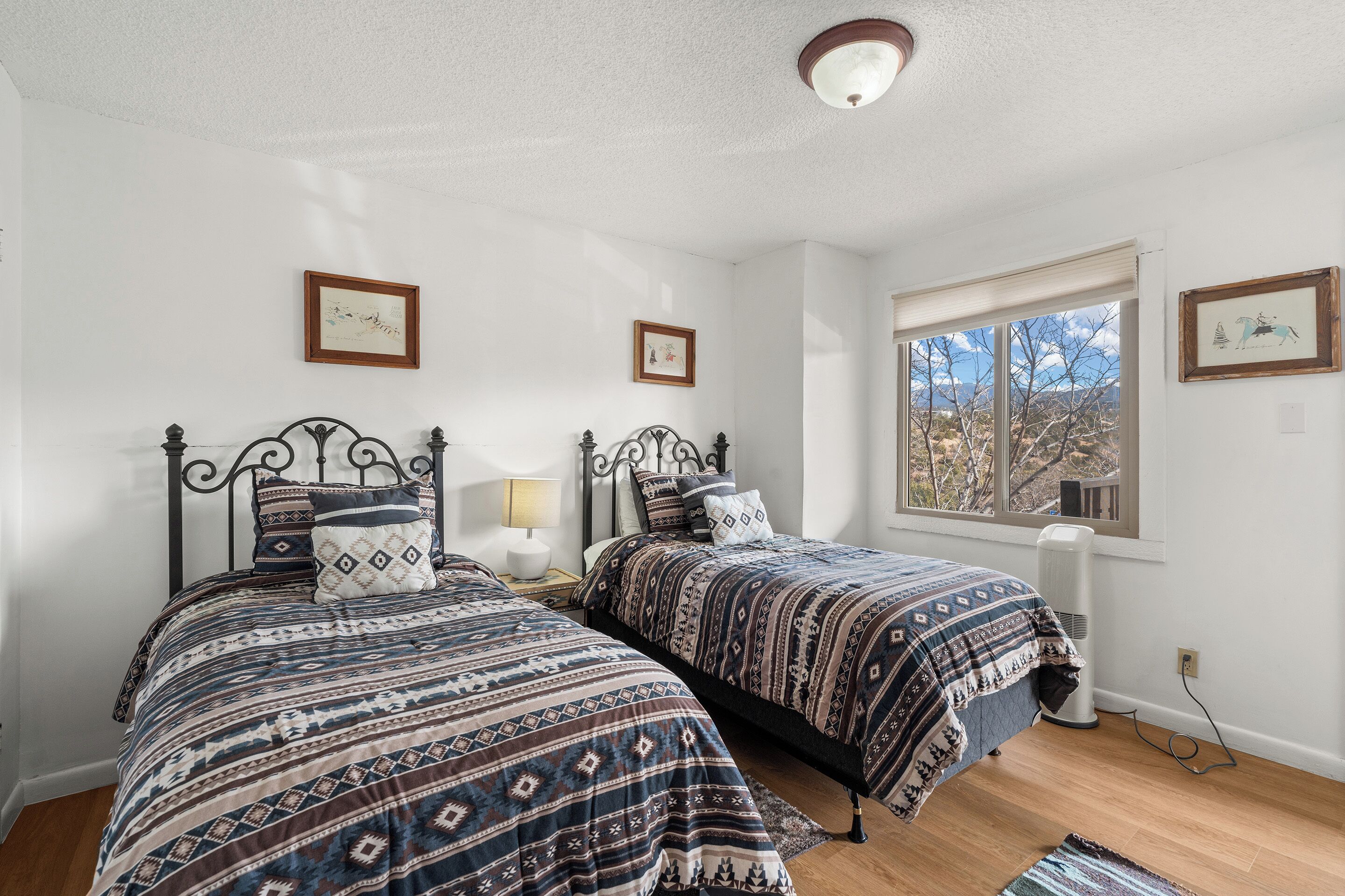 A bedroom with two beds, a window, and a ceiling light.