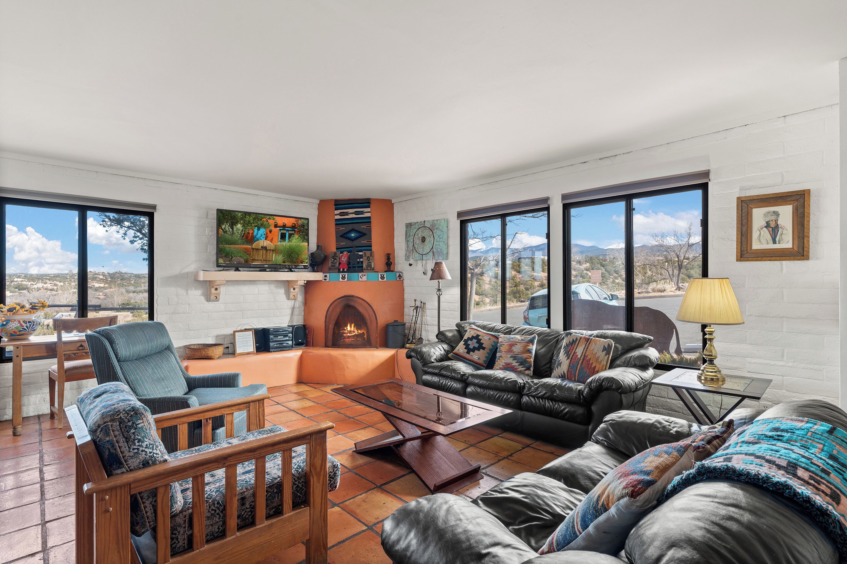 A spacious living room with a fireplace, large windows, and a view of the mountains.