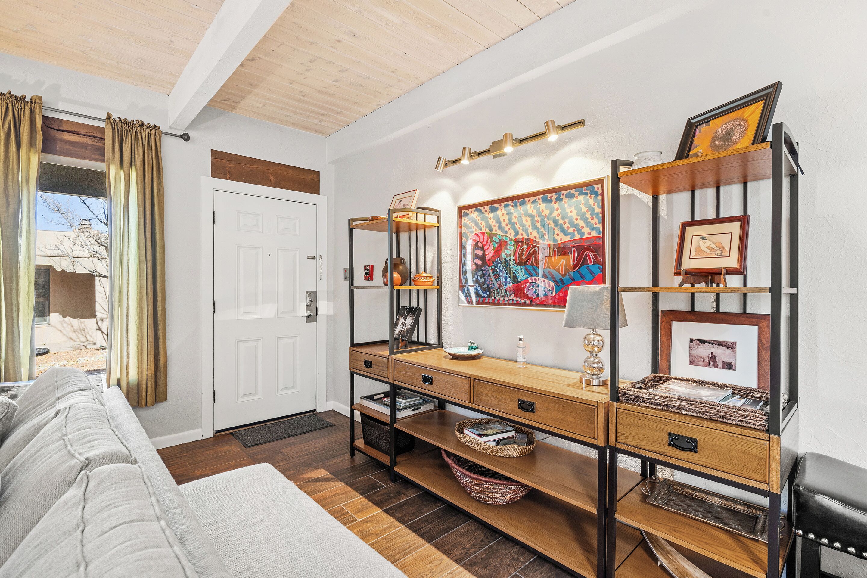 A living room with a sofa, wooden coffee table, and a wall-mounted shelf with decorative items.