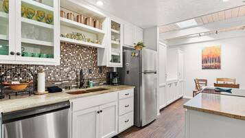 A modern kitchen with white cabinetry, a stainless steel refrigerator, and a mosaic backsplash.