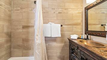 A bathroom with a wooden tiled wall, a white bathtub, a wooden vanity with a sink, and a mirror.