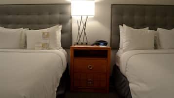Une chambre d’hôtel avec deux lits, une table de chevet avec une lampe et une horloge.