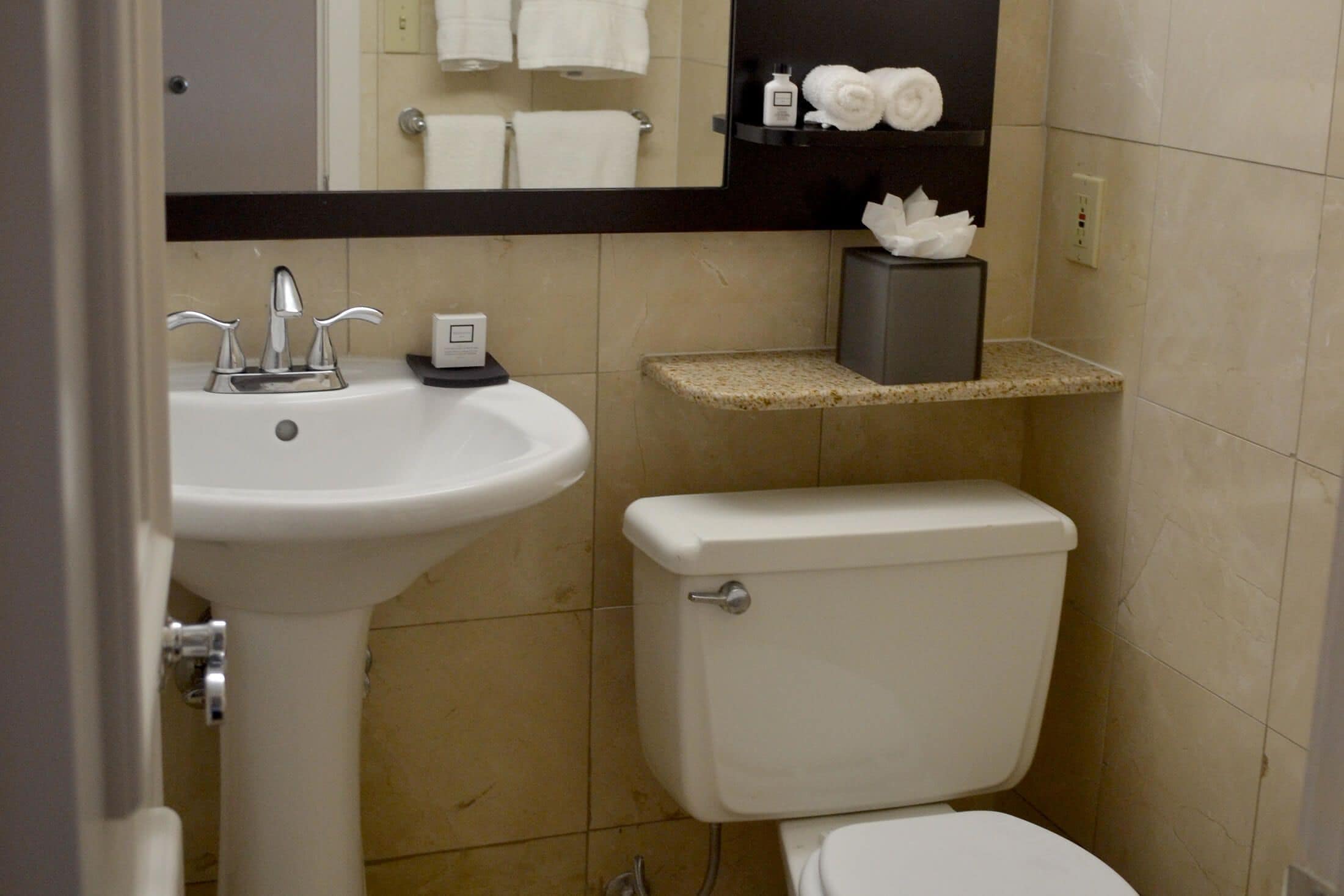 A bathroom with a white sink, a toilet, and a mirror above the sink.