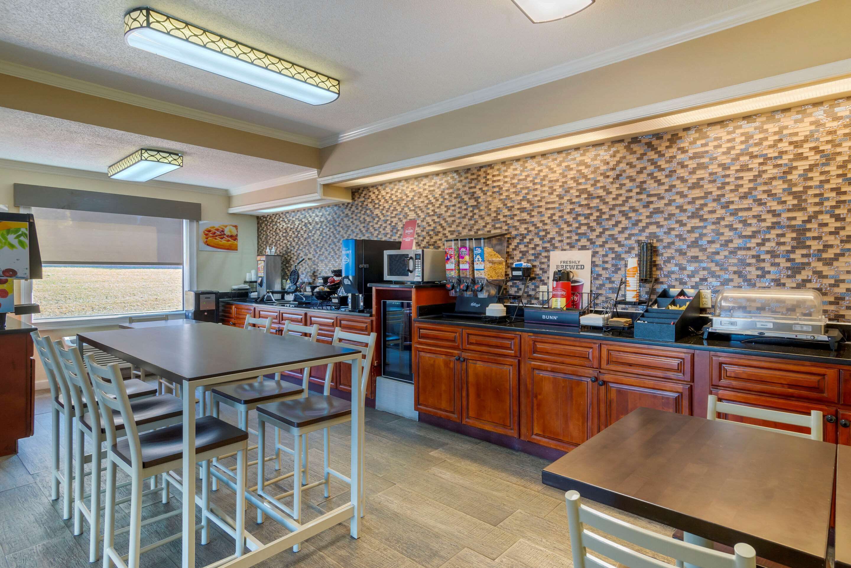 A modern kitchen with wooden cabinets, a built-in microwave, and a coffee station.
