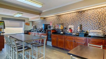 A modern kitchen with wooden cabinets, a built-in microwave, and a coffee station.