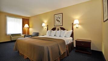 Habitación de hotel con una cama grande, dos mesitas de noche, un escritorio y una silla. Hay dos lámparas de pared y una ventana con cortinas.