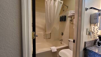 A bathroom with a bathtub, toilet, and a shower curtain.