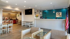 Un vestíbulo de hotel con mostrador de recepción, zona de estar y una cocina al fondo.
