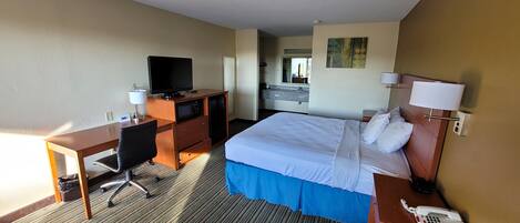 A hotel room with a bed, desk, chair, television, and a telephone.