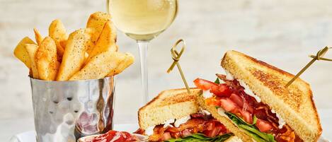 A plate with a grilled sandwich, fries, a glass of white wine, and a small container of ketchup.