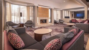 Un salon moderne doté d’une cheminée, de sièges confortables et d’un téléviseur à écran plat.