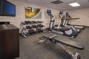Un gimnasio con cintas de correr, mancuernas y un banco.