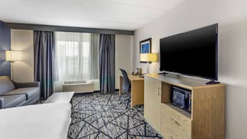A hotel room with a large bed, a desk, a television, and a microwave.