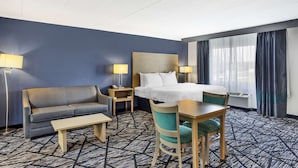 A hotel room with a bed, a sofa, a desk, and a chair. There are two bedside tables with lamps. The room has a patterned carpet and a large window with curtains. - Best Western Westgate Inn (York)