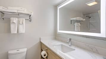 A modern bathroom with a white toilet, a marble sink, and a large mirror.