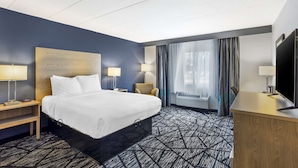 A hotel room with a bed, two bedside tables with lamps, a desk with a television, and a large window with curtains. - Best Western Westgate Inn (York)