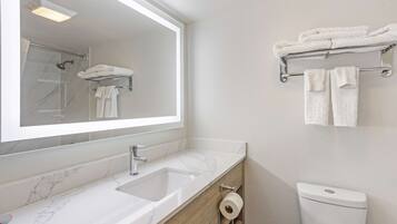 A bathroom with a marble sink, a mirror, a towel rack, and a toilet.