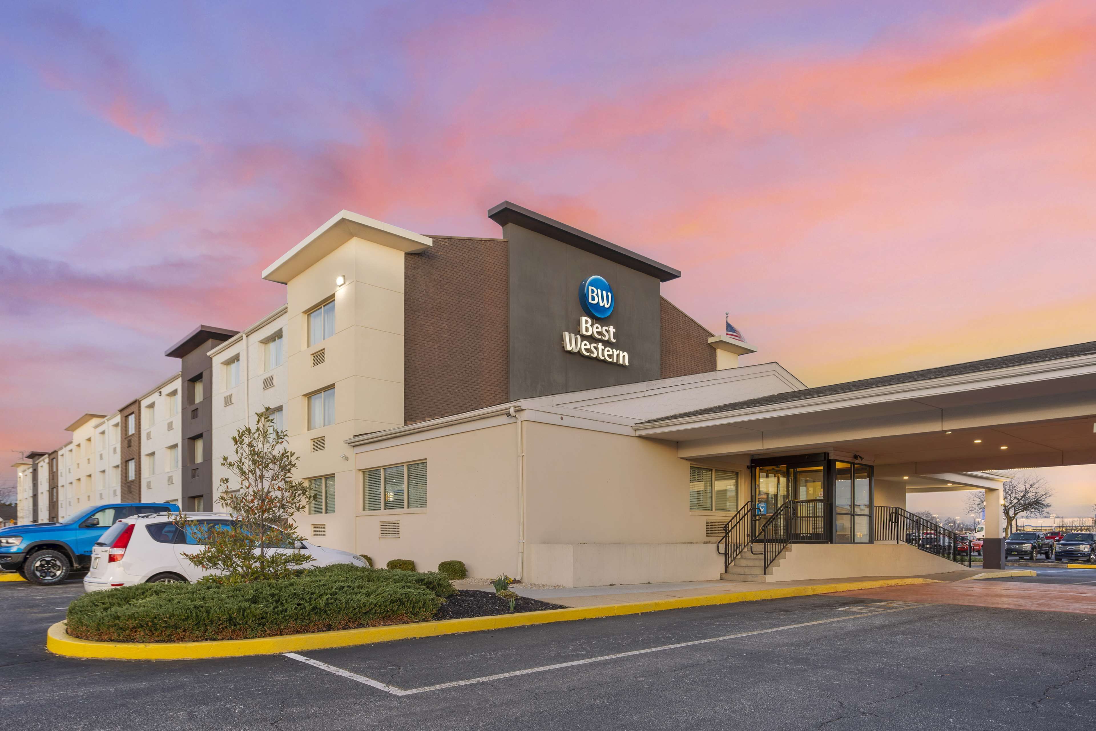 A Best Western hotel with a modern facade, a parking lot, and a clear sky.