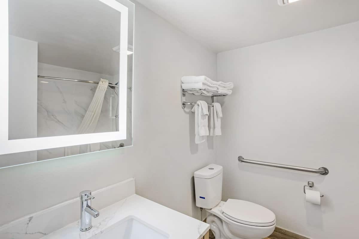 A modern bathroom with a marble sink, a toilet, a hand dryer, and a towel rack.