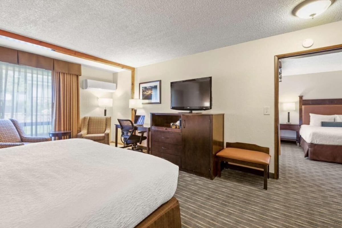 Une chambre d’hôtel avec un grand lit, un bureau avec une chaise, une télévision et une armoire.