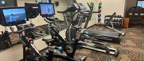 Et fitnesscenter med løbebånd, spinningcykler og et spejl.