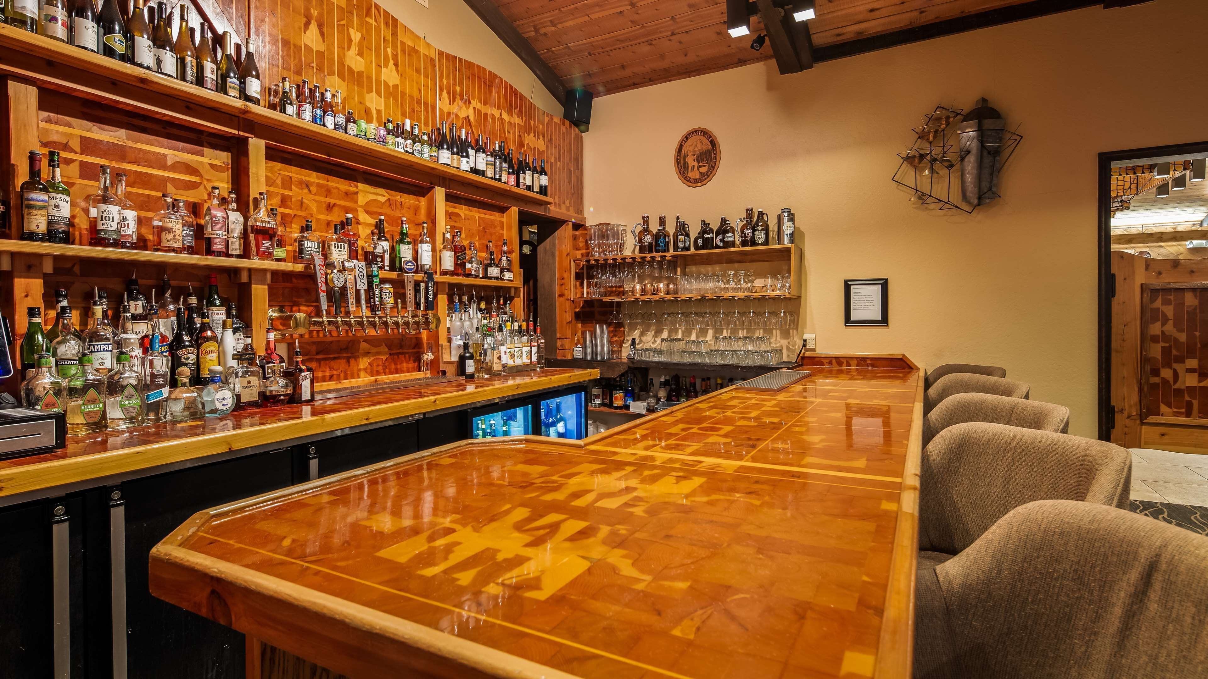 Un bar doté d’un comptoir en bois poli, d’étagères remplies de bouteilles d’alcool et d’une variété de verres.