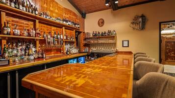 Un bar doté d’un comptoir en bois poli, d’étagères remplies de bouteilles d’alcool et d’une variété de verres.