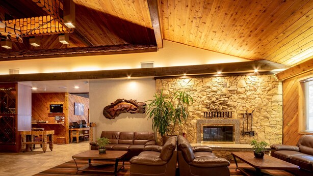 A cozy living room with a stone fireplace, leather sofas, and a wooden ceiling. - Best Western Plus Tree House (Mount Shasta)