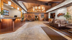 A spacious lobby with a wooden reception desk, leather sofas, and a stone wall. - Best Western Plus Tree House (Mount Shasta)