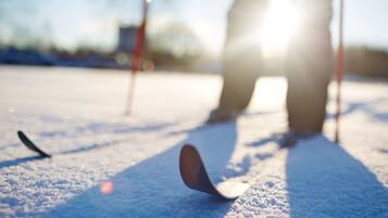 Uma pessoa praticando curling em uma superfície nevada, com uma pedra de curling e uma vassoura.