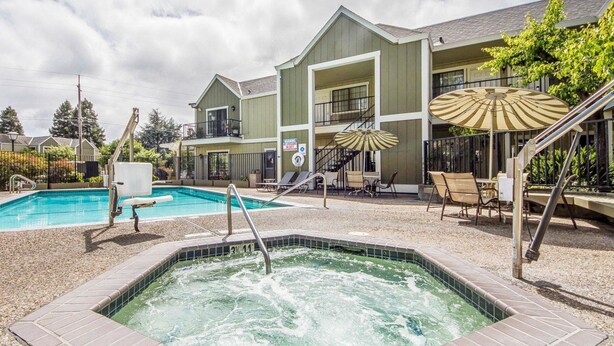 Ein Hotel mit Schwimmbad, Whirlpool und Sitzgelegenheiten im Freien mit Sonnenschirmen.