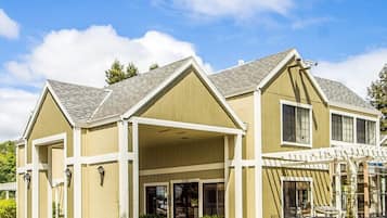 A two-story building with a covered entrance and a patio area with outdoor seating.