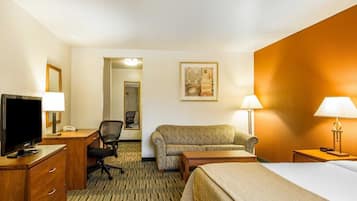Une chambre d’hôtel comprenant un lit, un bureau avec une télévision, une chaise, un canapé et une lampe.