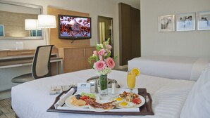 A hotel room with a dining table set with breakfast, a TV on the wall, and a bed. - Holiday Inn Washington-Central/White House by IHG (Washington)
